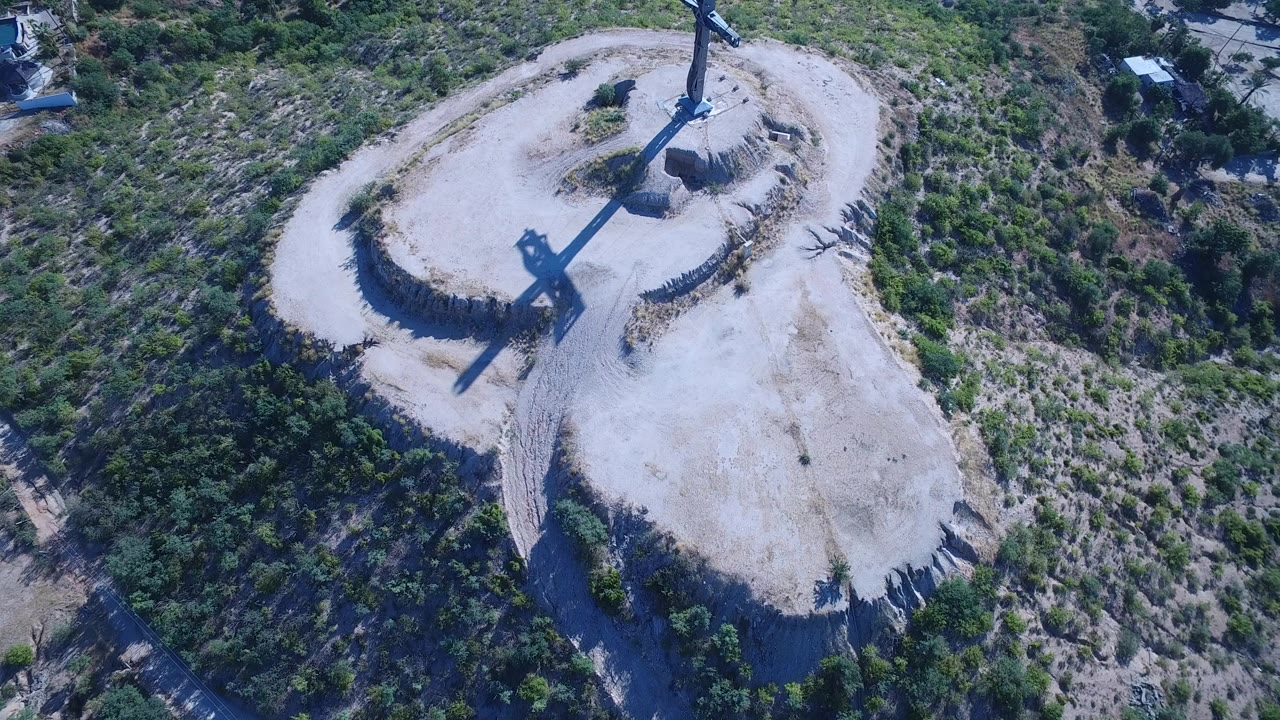 Aerial view of a dirt loop around a tall pole on scrubby hillside.