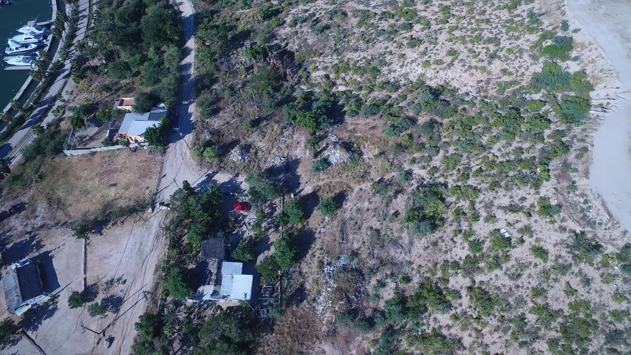 Overhead view of marina boats, dirt roads, scrubland, and low buildings.