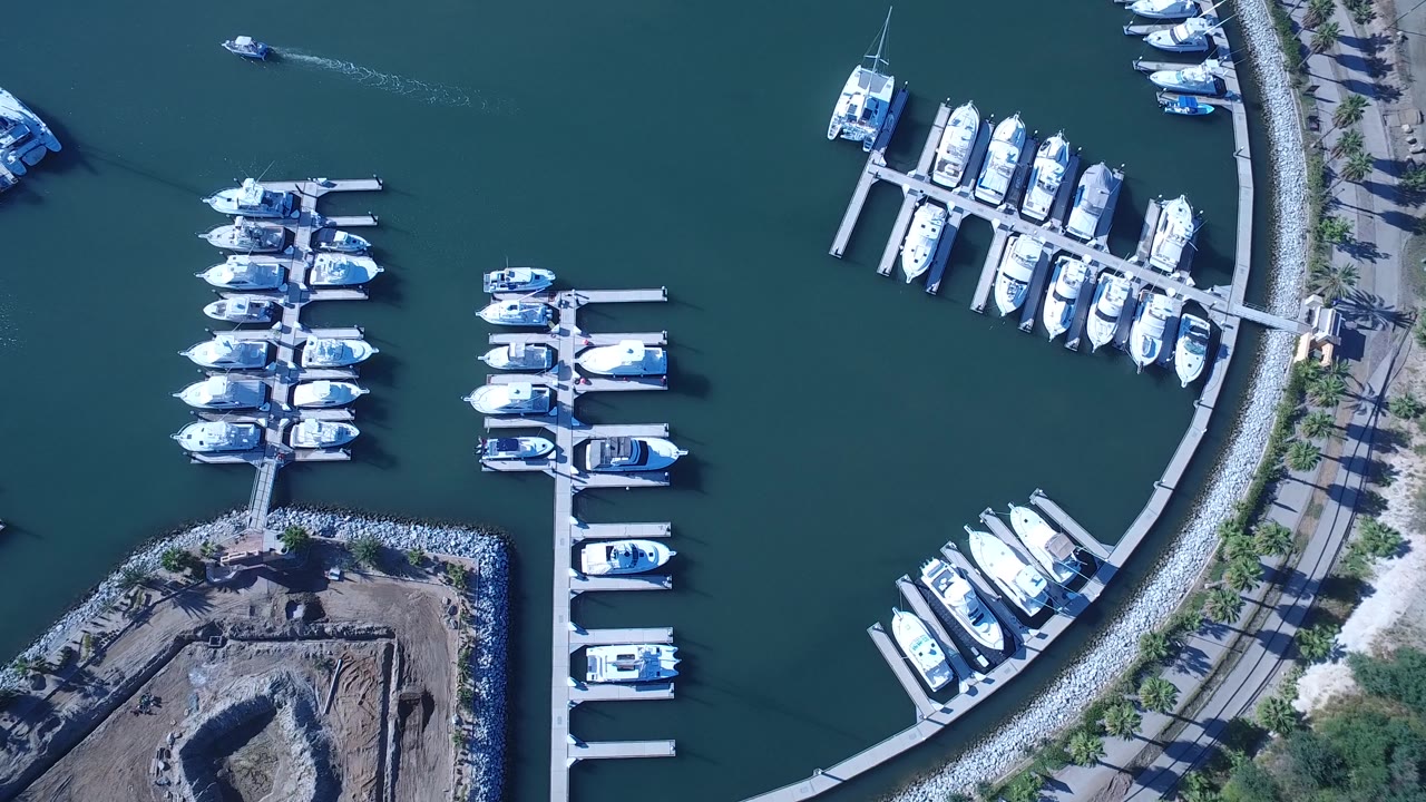 Top-down marina view with boat slips and wake on blue water