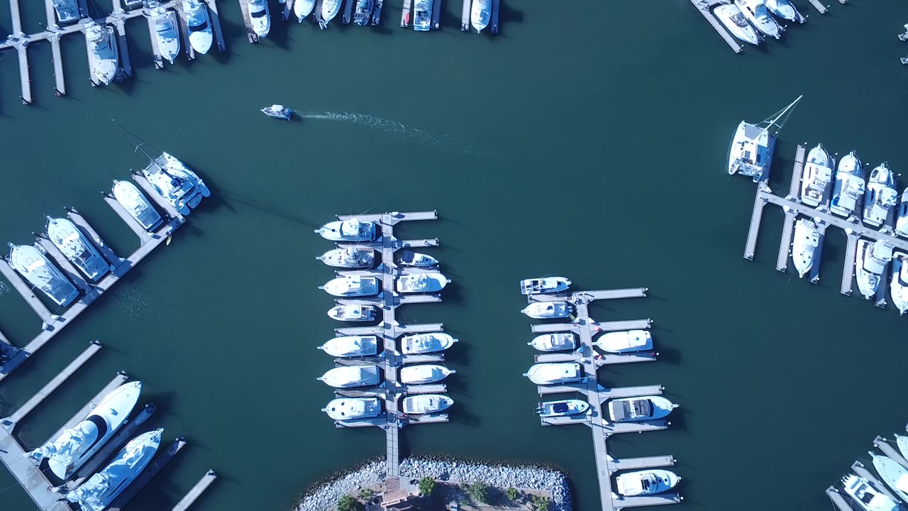 Drone view of marina docks and grouped boats over green-blue water.