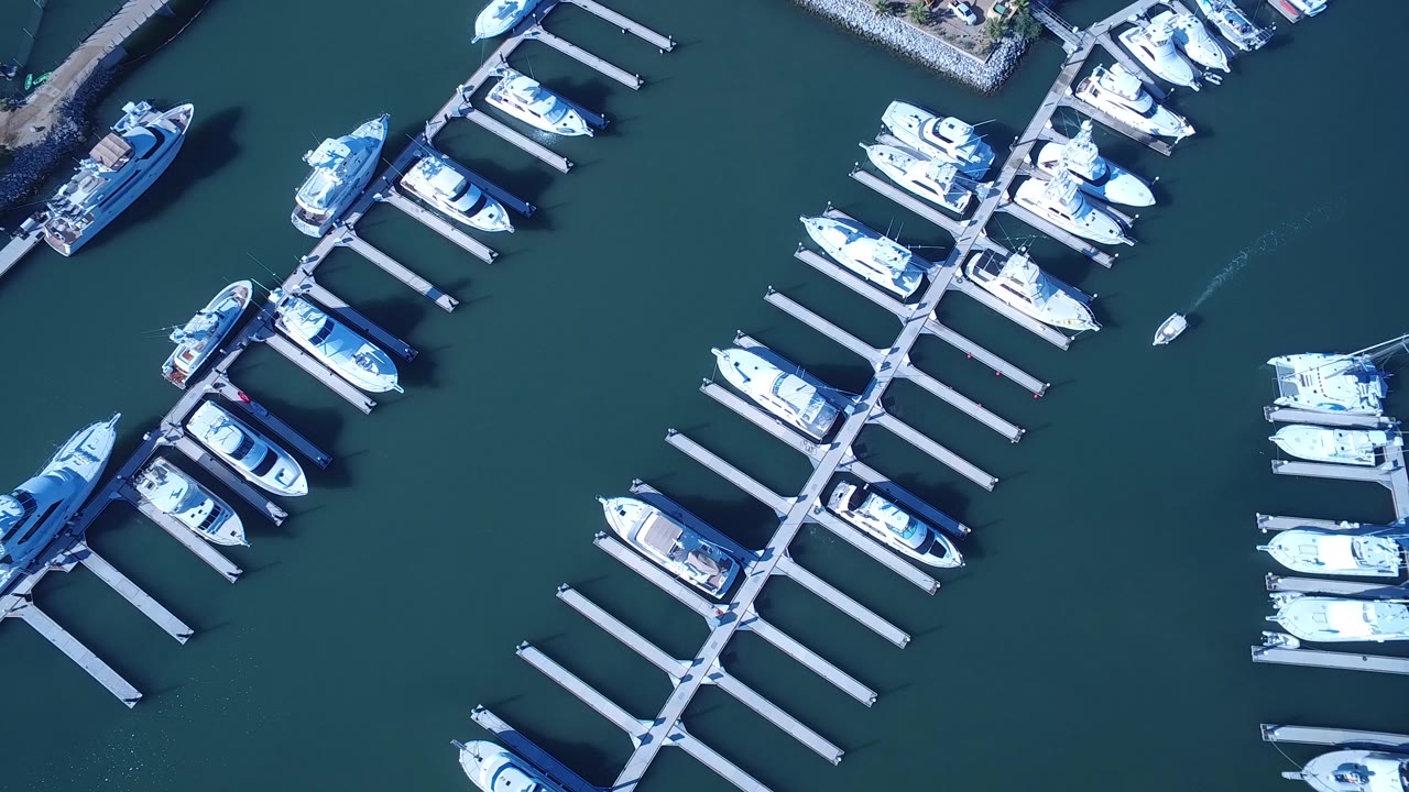 Aerial frame over Playita with diagonal dock fingers, several white cruisers, open teal water around the slips, and no visible people.
