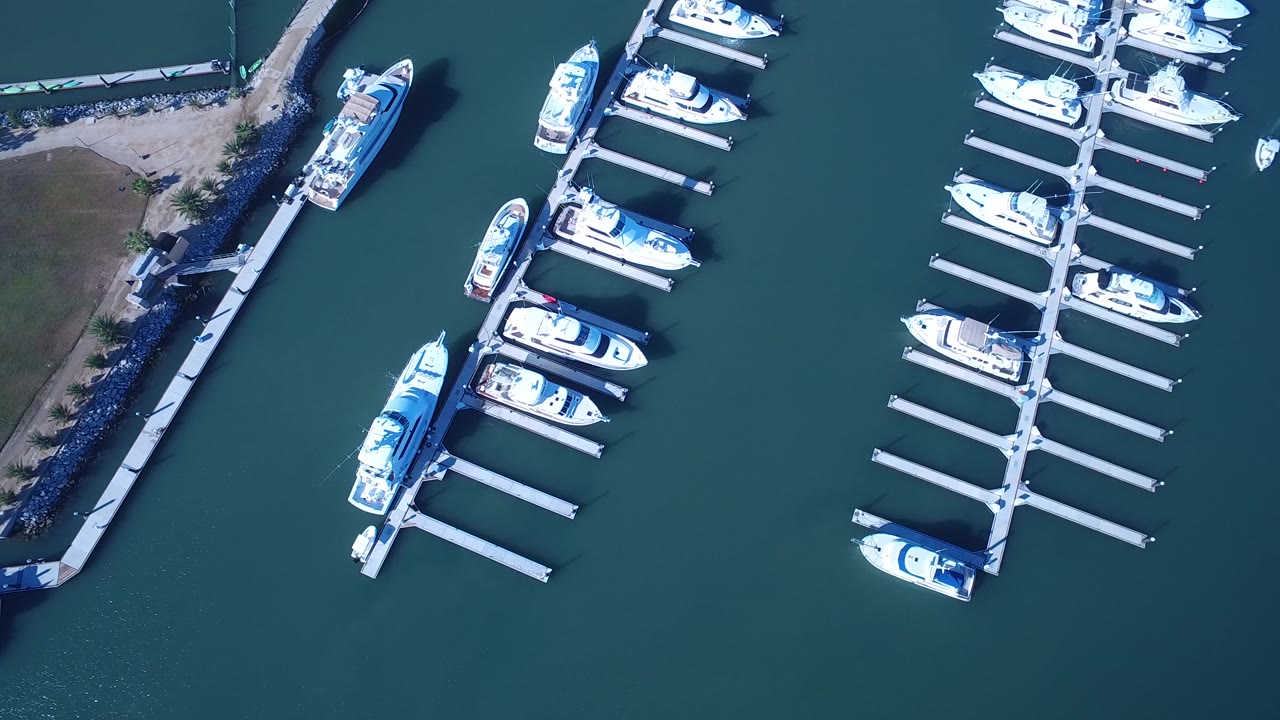 Overhead marina docks with boats beside teal water and shoreline.