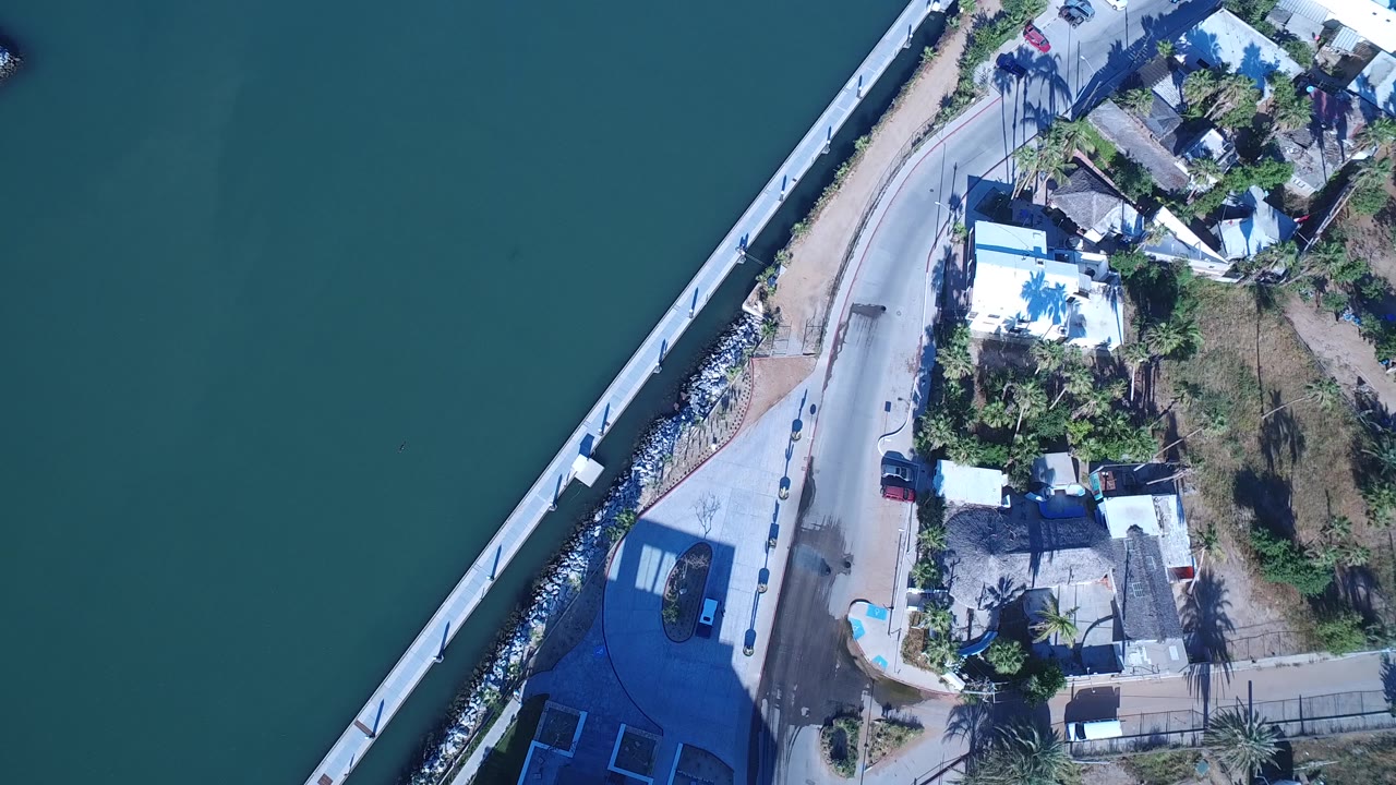 Overhead marina road beside teal water and a bridge edge.