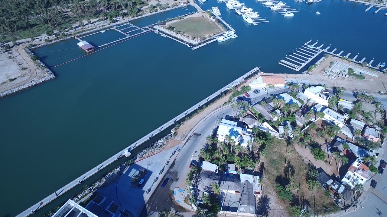 Aerial view of canal water, roads, low buildings, docks, and marina slips.