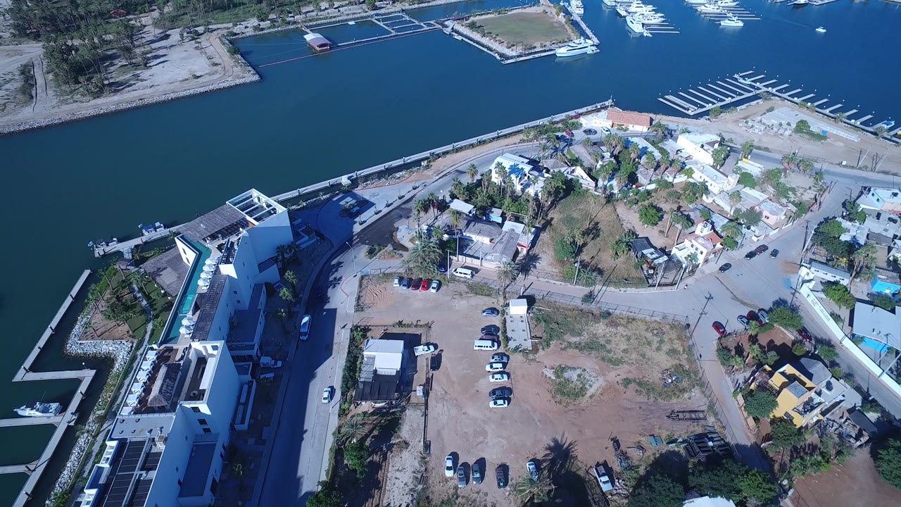 Aerial view of marina water, docks, waterfront buildings, roads, and dry lots.