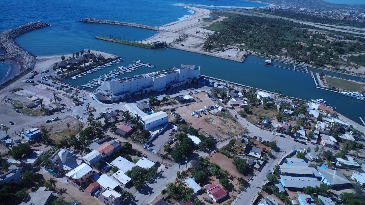Aerial harbor with seawalls, docks, boats, beach, and nearby homes.
