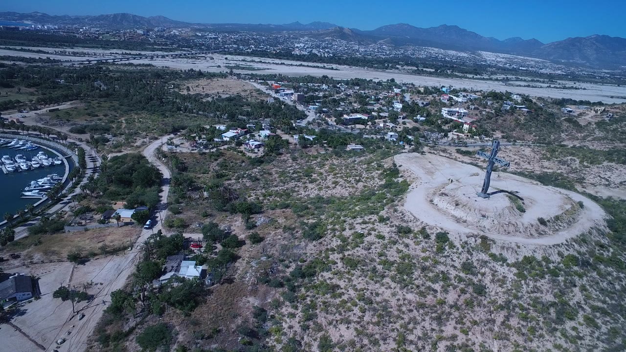 Aerial view of scrubland, buildings, marina water, and mountains