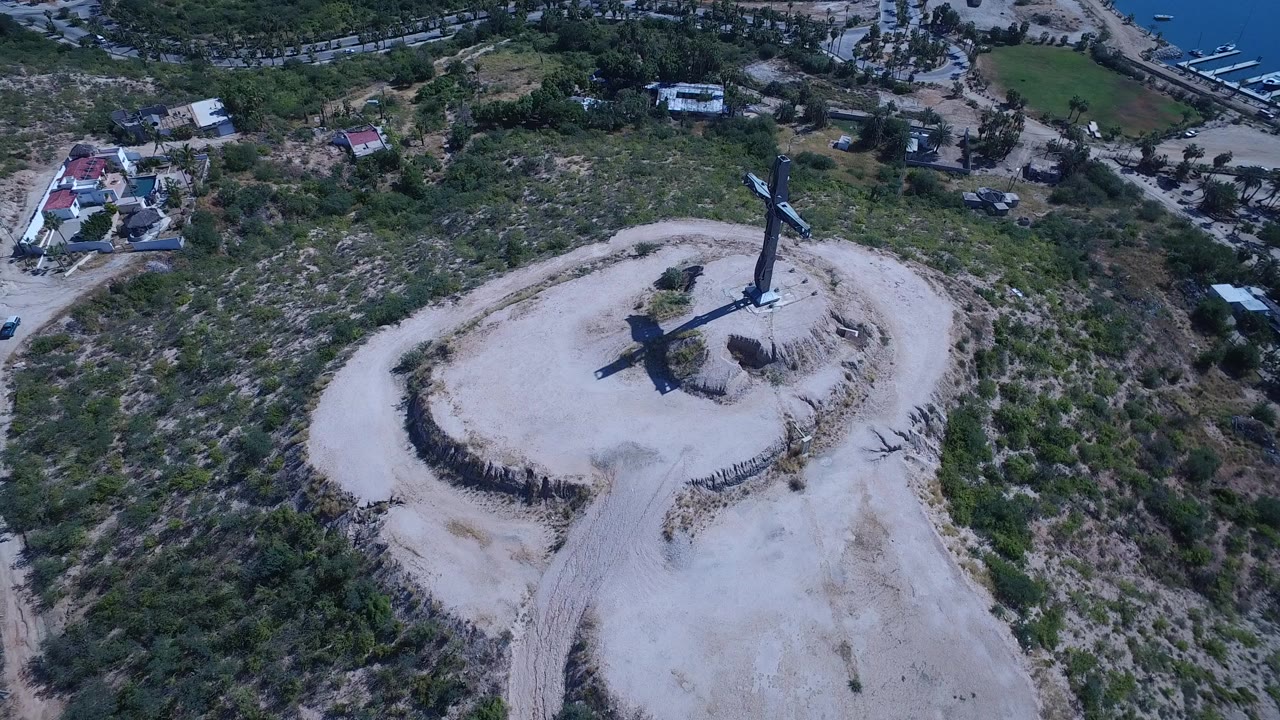 Blue cross on a pale desert hill seen from above.