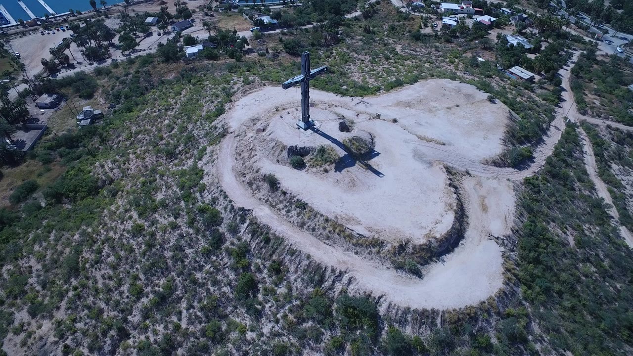 Aerial view of a crucifixion monument on a pale rocky hilltop.