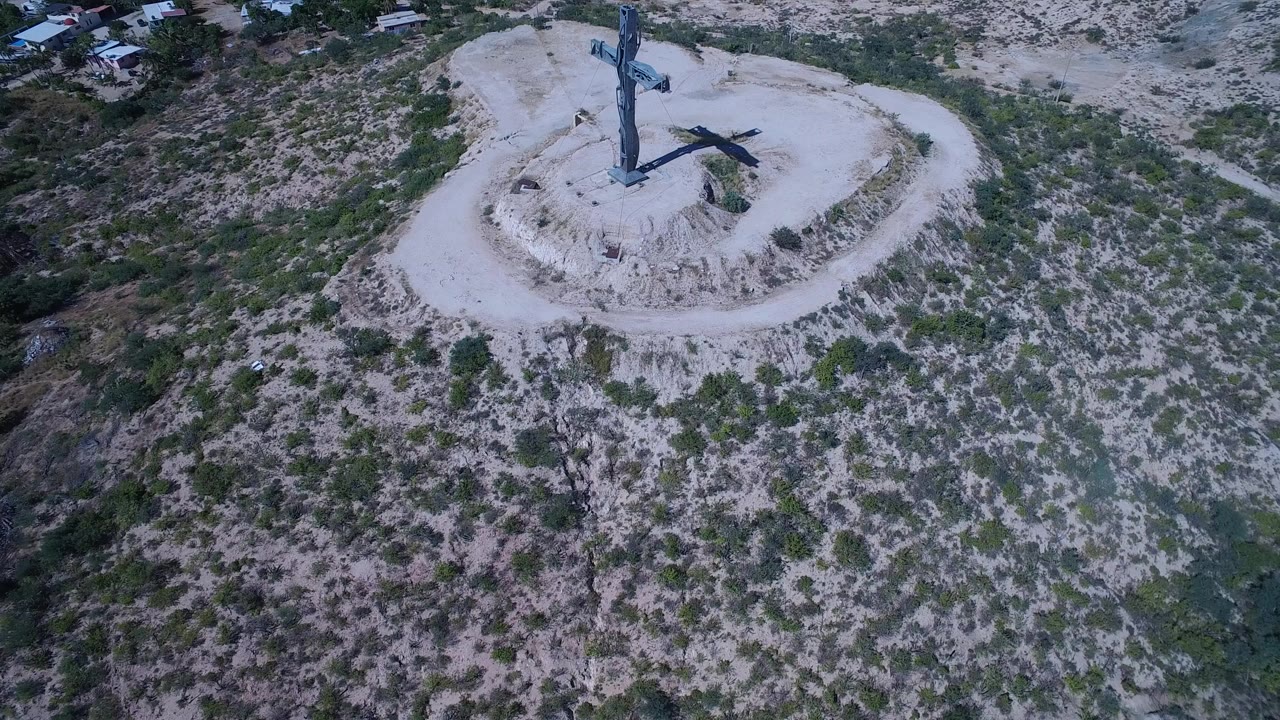 Aerial view of a crucifixion monument on a rocky grassy hill.