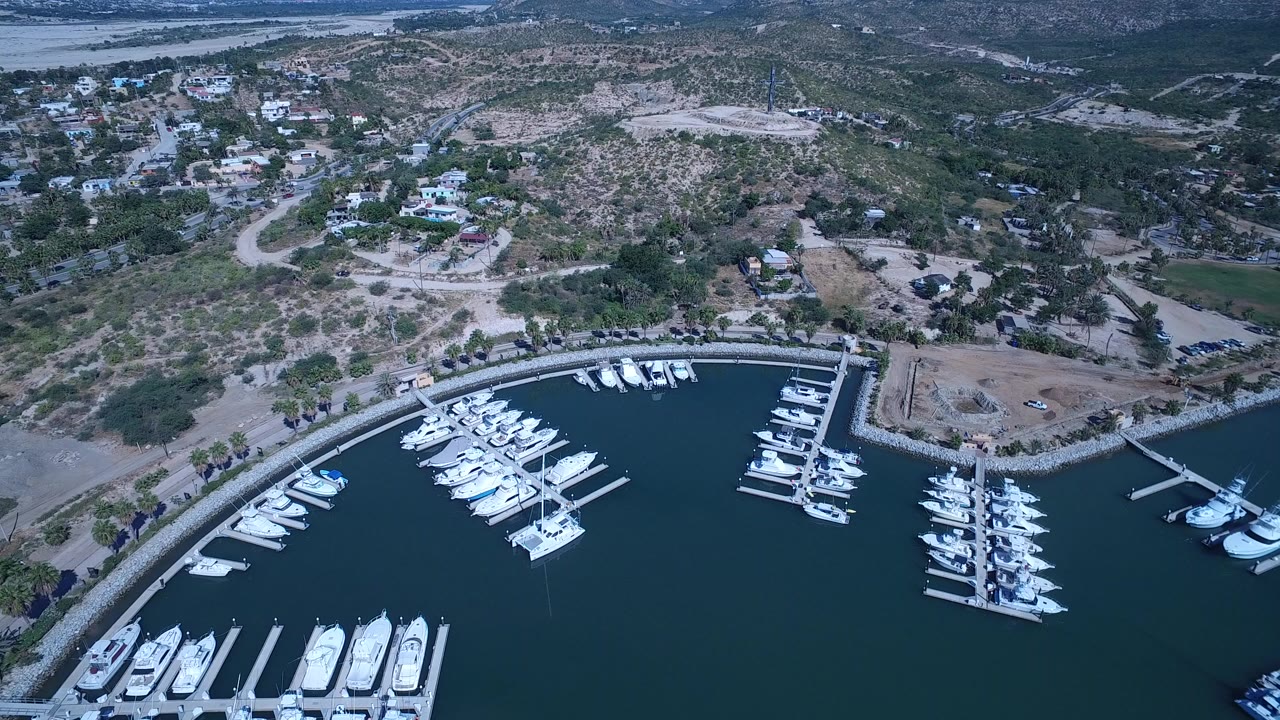Aerial marina with rows of white boats beside dry hillside roads.
