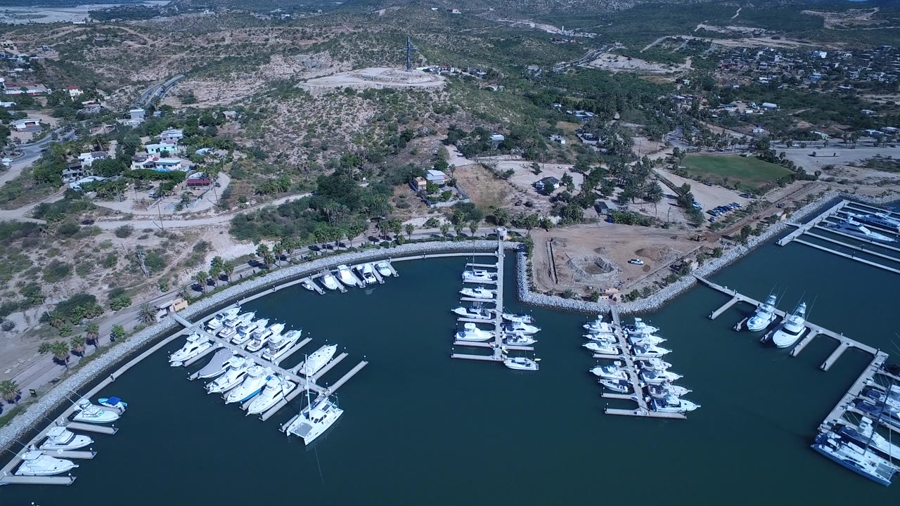 Aerial view of marina docks, white boats, curved shoreline, and dry hills.