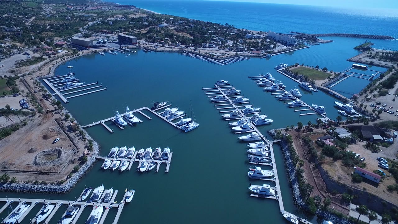 Marina basin with several rows of boats and a breakwater near the ocean.