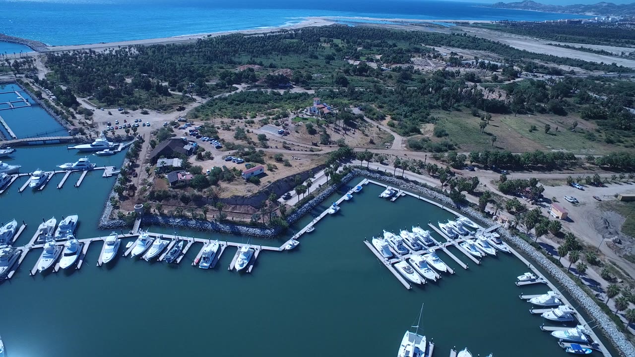Aerial marina with yachts, docks, beach, and ocean beyond.
