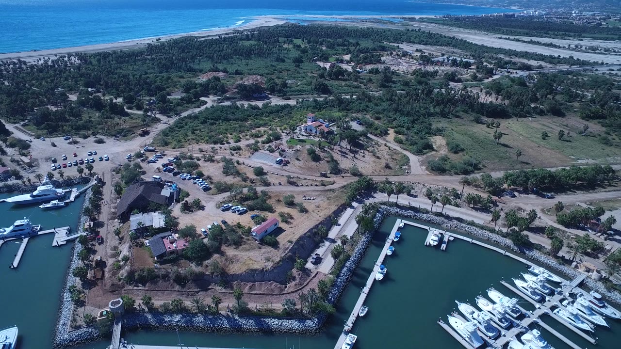 Drone view of marina corner, parking area, trees, and beach.