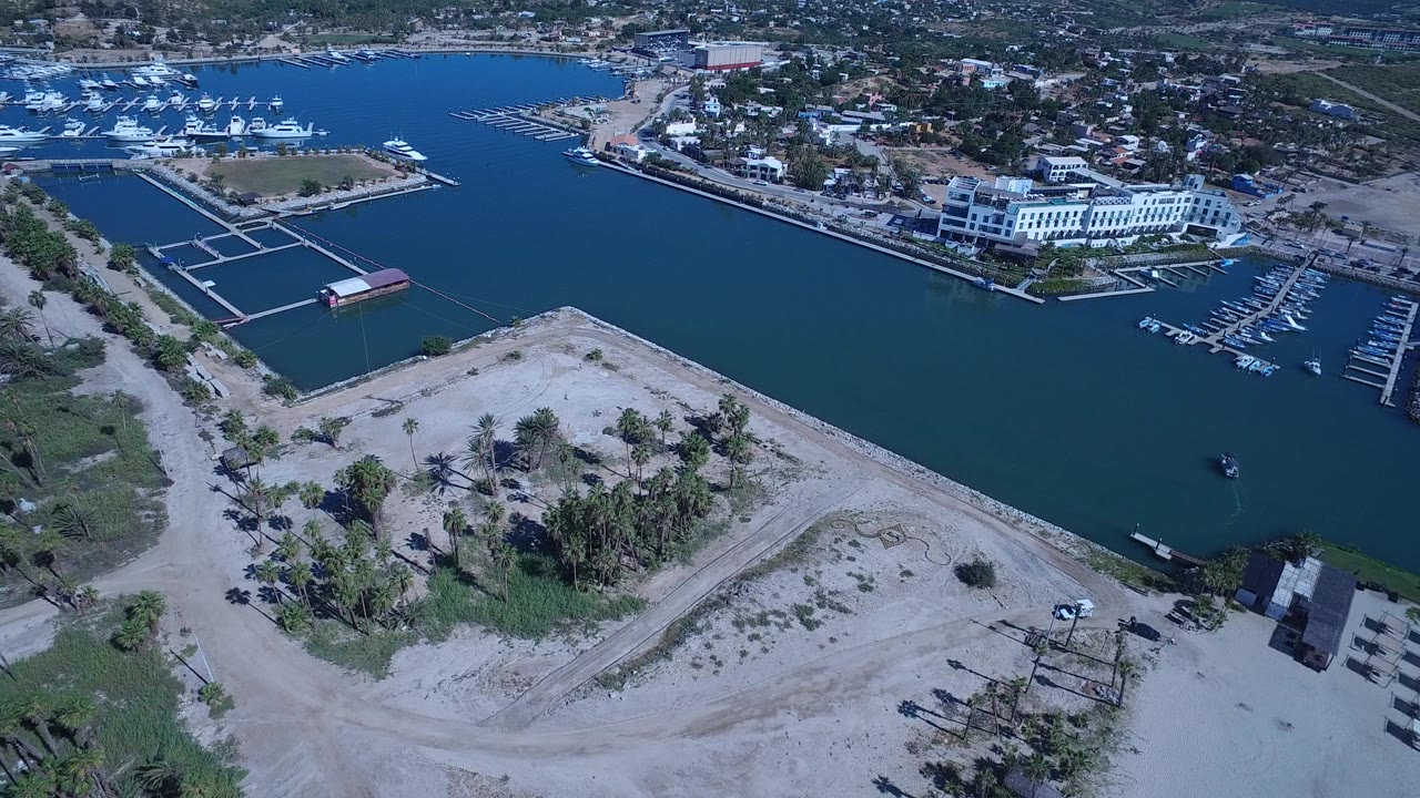 Aerial view of marina water, sandy shore, docks, and coastal buildings.