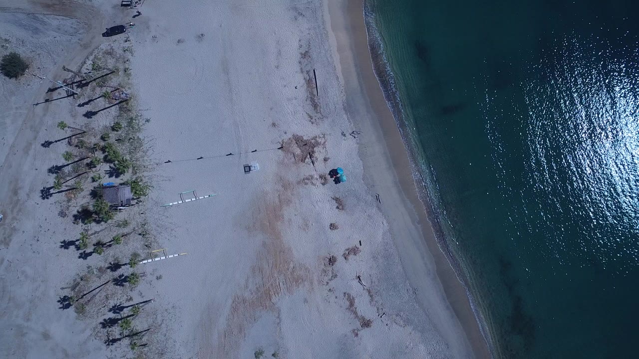 Top-down aerial view of sand beach beside dark teal water