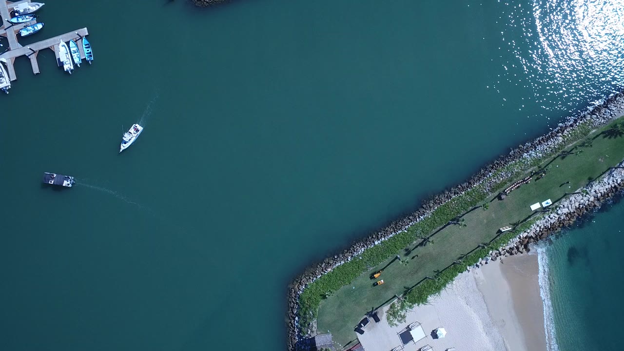 Overhead marina water with boats, docks, rocky point, and beach edge.