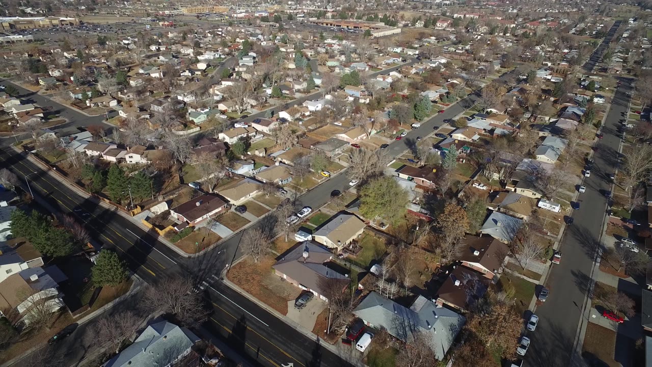Drone-style view across homes, roads, yards, parked cars, and bare trees.