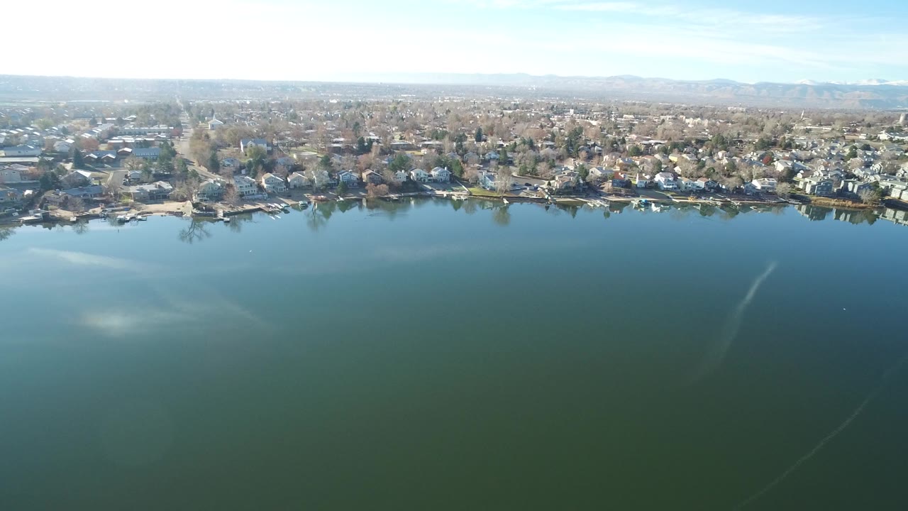 Aerial view of green-blue water beside a suburban shoreline.