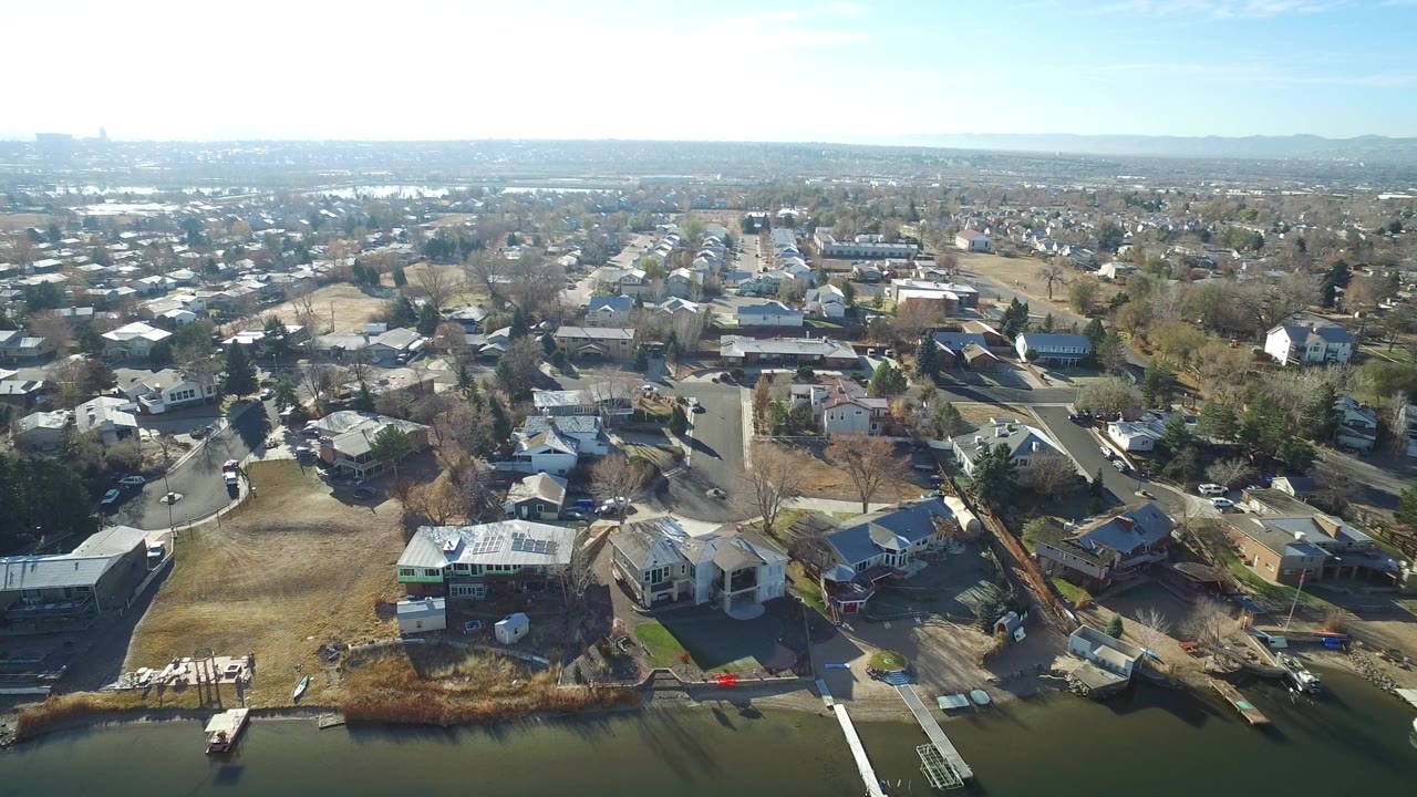 A high view over Westminster, Colorado shows a residential street grid, detached houses, winter trees, a water edge at the bottom, and no visible people.