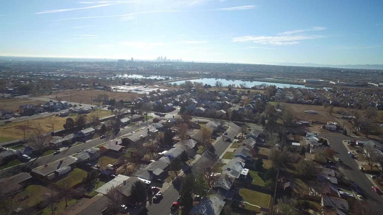 Aerial view of residential streets, homes, water, and distant skyline.