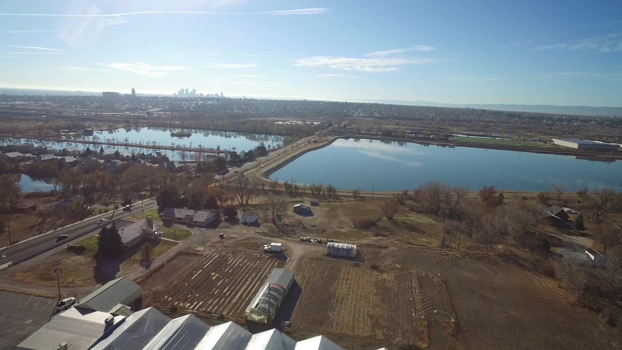 Aerial view of a lake, fields, houses, roads, and distant skyline.
