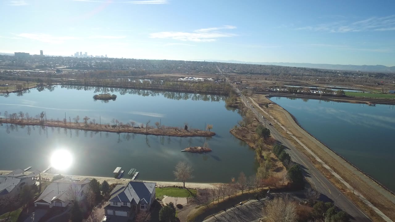 Aerial view of a road crossing blue water with homes in the foreground
