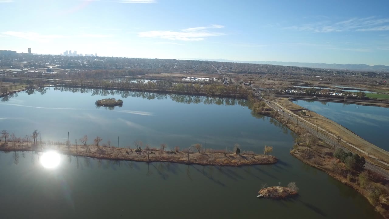 Aerial view of water basins divided by a long road under bright sun.