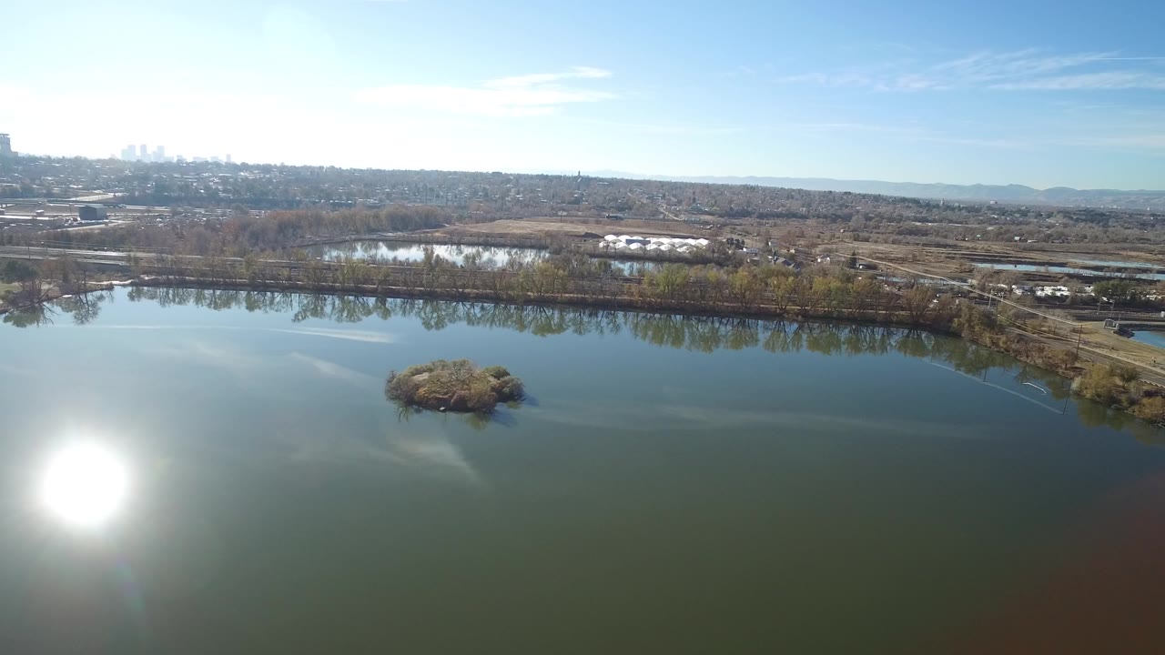 Aerial view of a pond with sun glare and a small island.