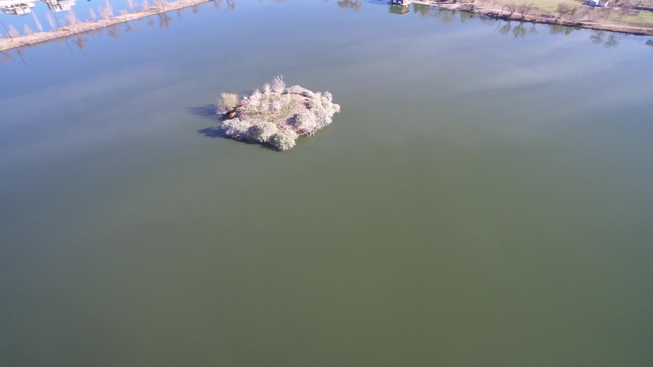 Aerial view of a small island in a green-blue lake
