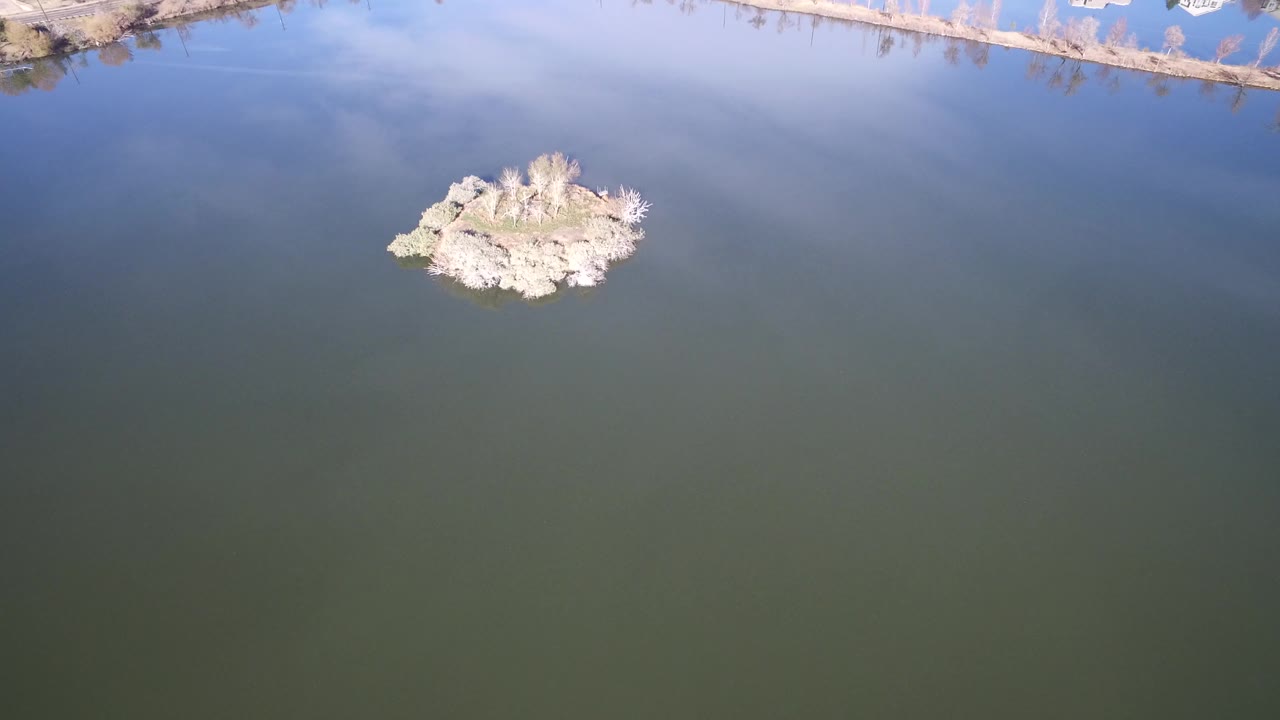 Brushy island and shoreline appear above a large expanse of calm water.