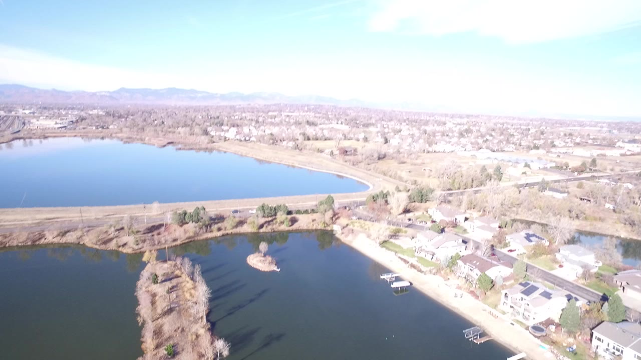Aerial view over lakes, suburban homes, and distant mountains.