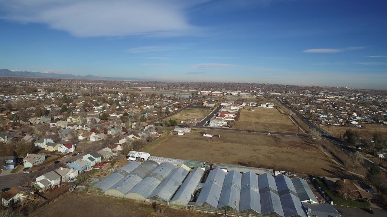 Aerial view of pale arched sheds beside homes and open fields