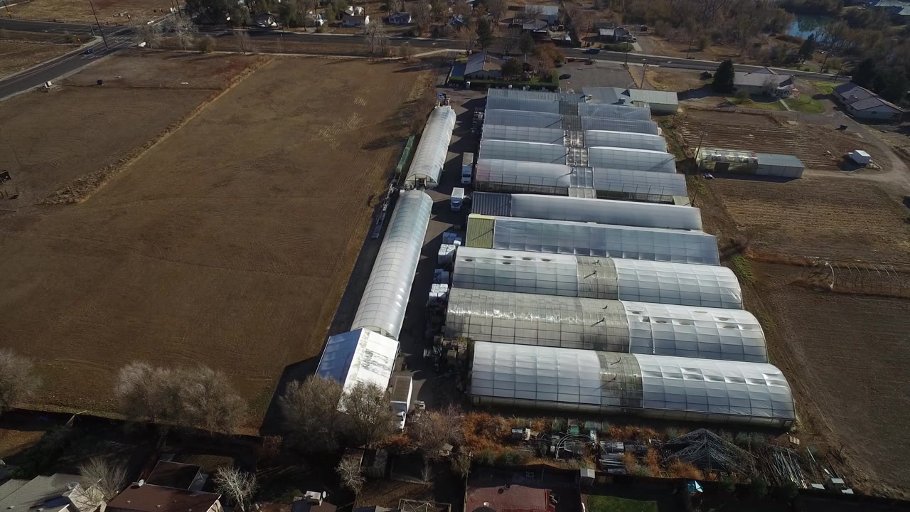 Greenhouse structure complex seen from above with roads and homes nearby.