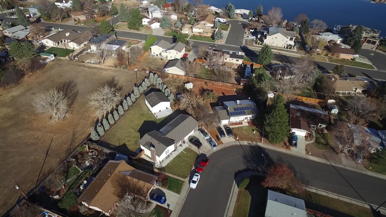 Aerial view of suburban homes beside a curved street and open grass