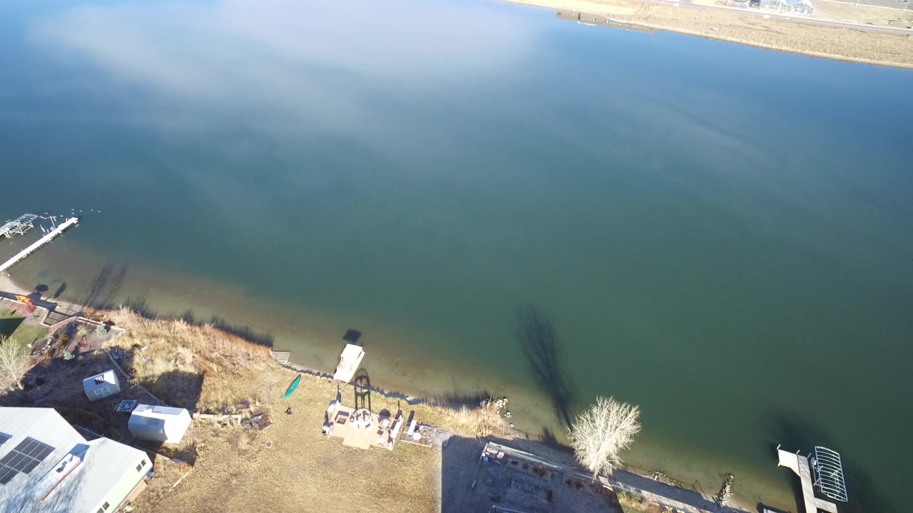 High-angle lake shoreline with docks, homes, and a small boat at the left edge.