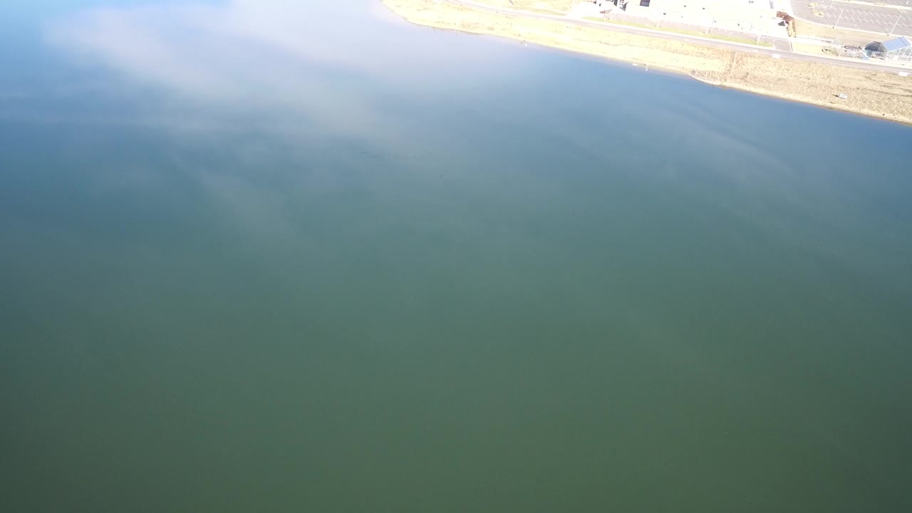 Blue-green water with a pale shoreline and road at the top edge.
