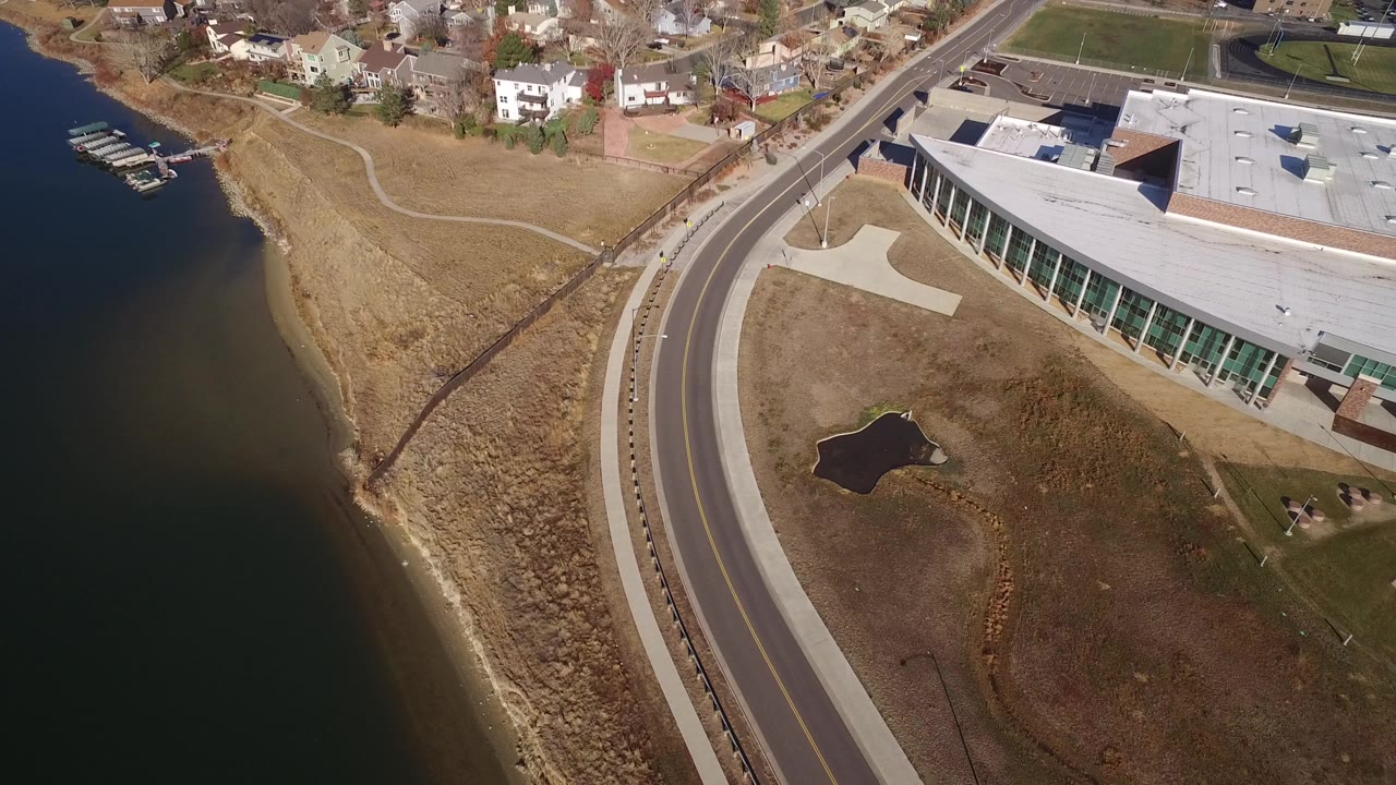 Aerial view of a curving road beside water and a large modern building.
