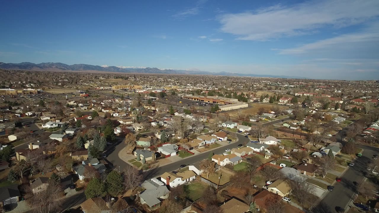 Aerial view of suburban homes under a blue sky with distant mountains.