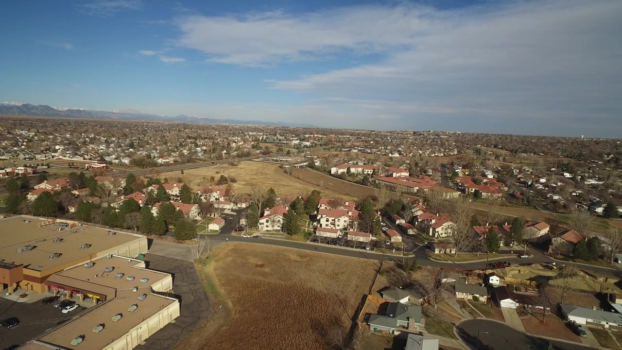 Elevated view over suburban homes, dry fields, and distant mountains.
