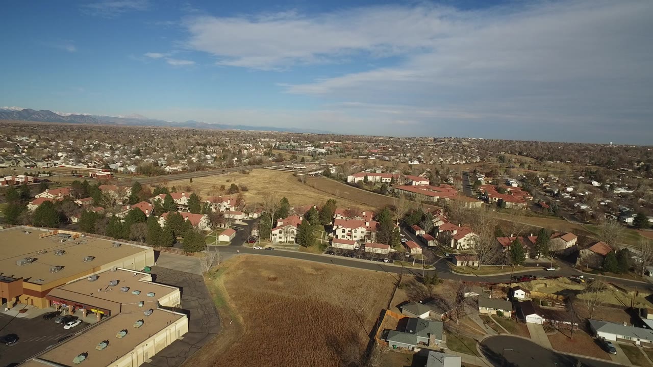 Second frame holds a wide Westminster, Colorado neighborhood panorama with a tan roof in the foreground, curving residential streets, red-roofed homes, dry fields, distant mountains, and no visible people.