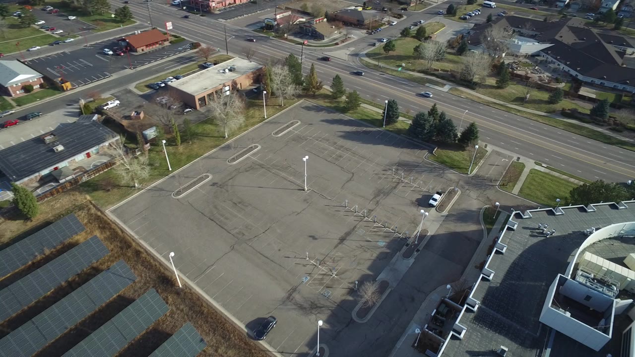Aerial view of a mostly empty parking lot beside a multi-lane road.