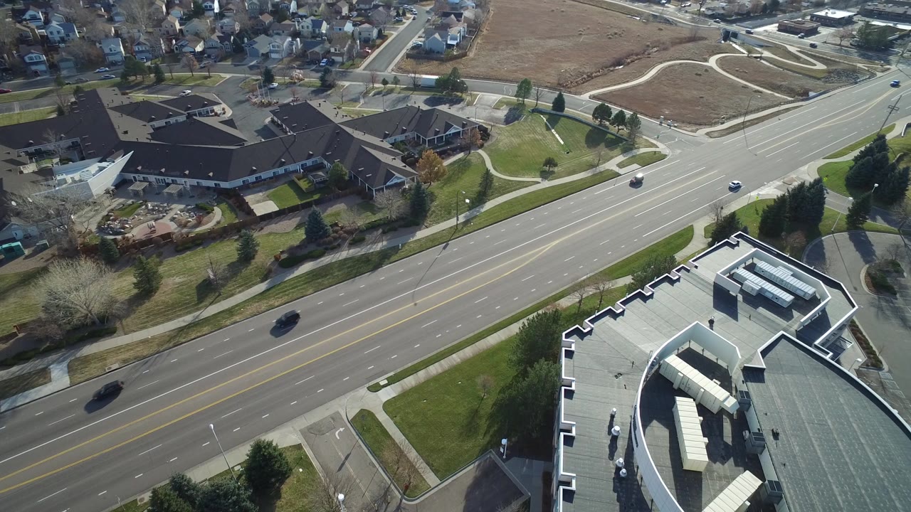 A second Westminster aerial view keeps the divided road and curved-roof building prominent, with residential blocks and open ground beyond and no visible people.