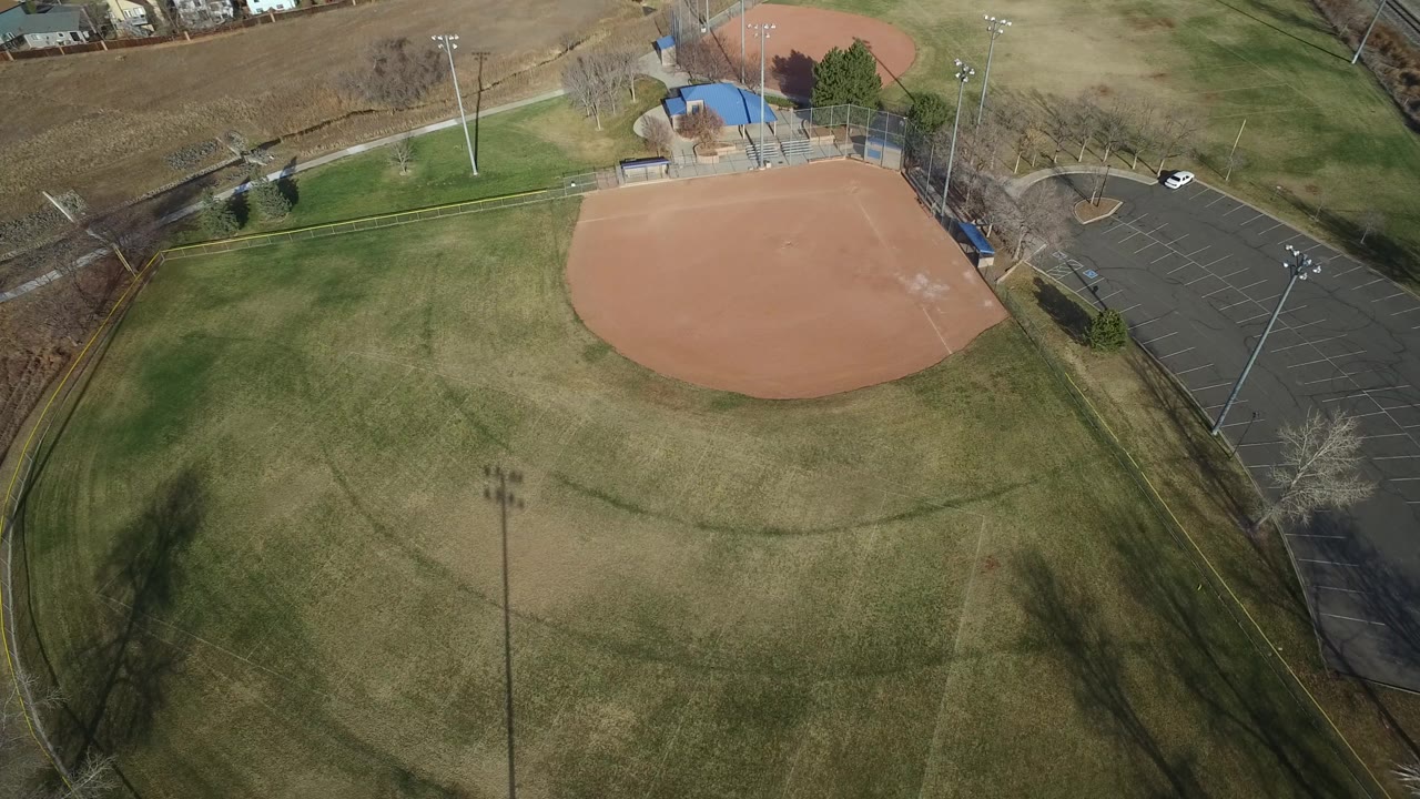 Aerial view of an empty baseball field beside a parking lot.