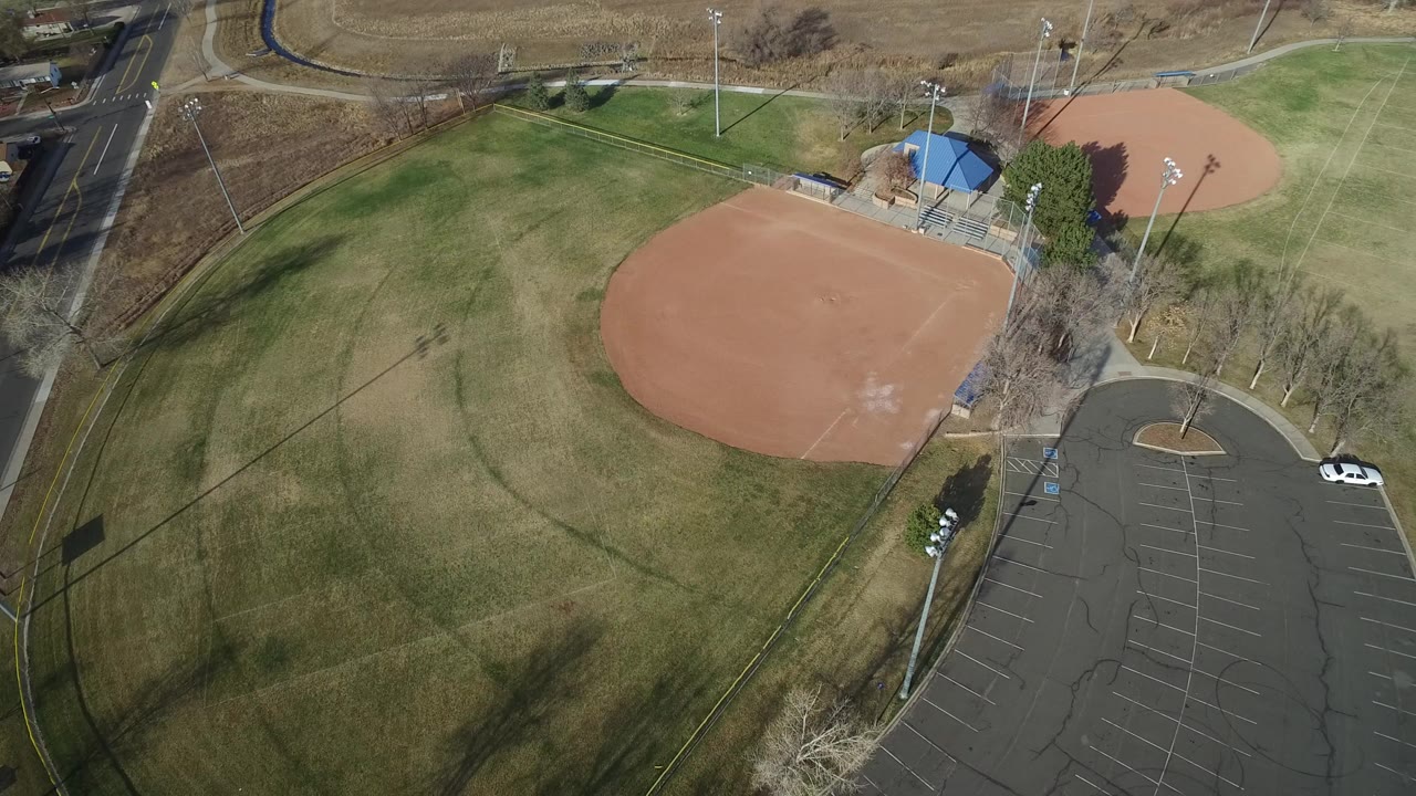 Aerial view of an empty baseball field beside a parking lot.