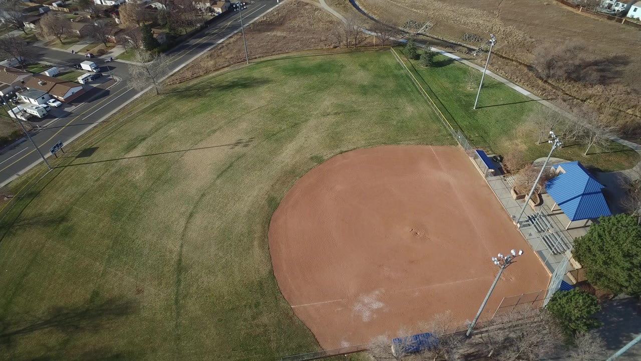 Aerial view of an empty baseball diamond beside grass and streets.