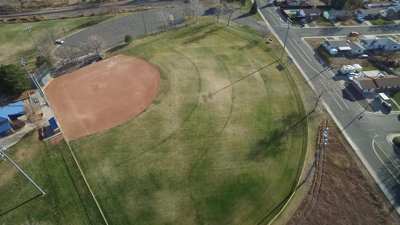 Aerial view of a baseball diamond beside grass and a road.