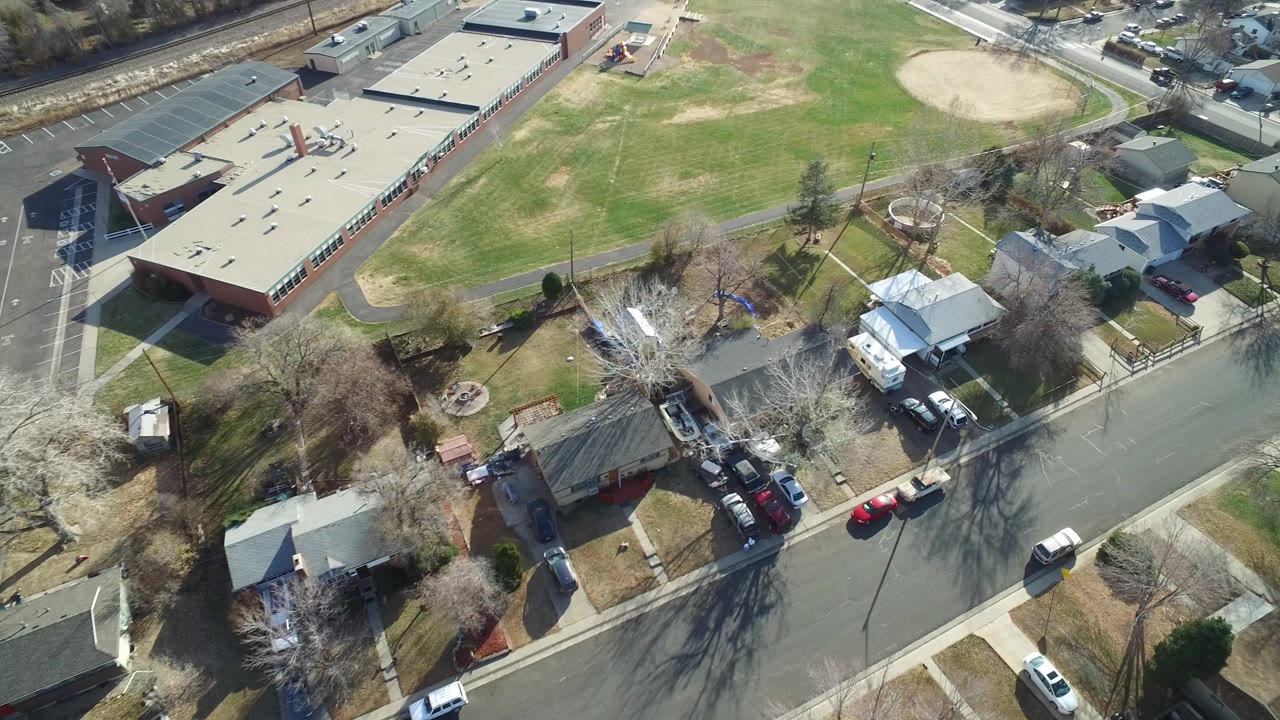 Aerial view of a school building, neighborhood street, homes, and grass fields.