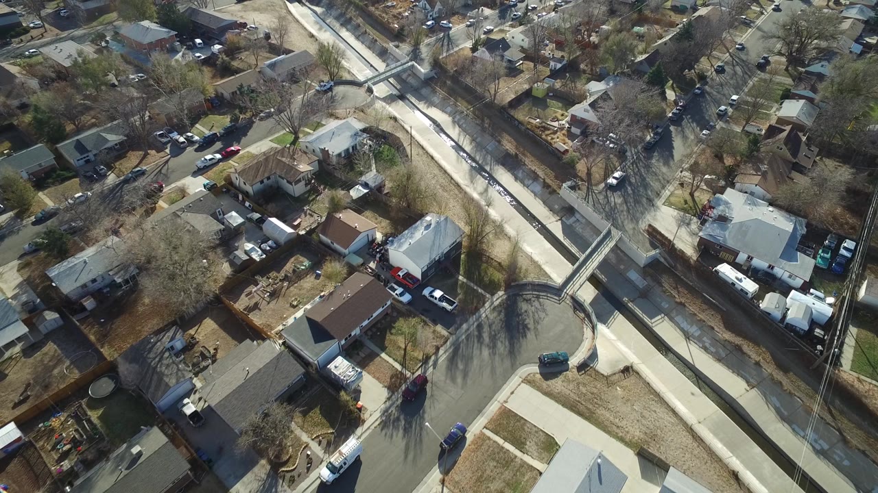 Overhead residential blocks with a canal, bridge, rooftops, and parked cars.